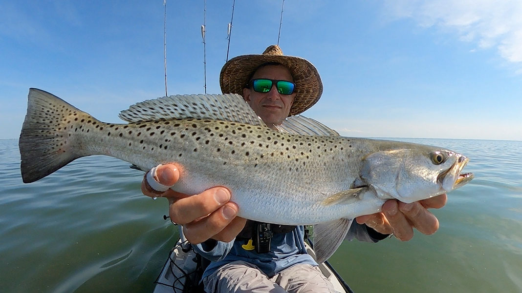 man holds up speckled trout caught by kayak in Chesapeake Bay