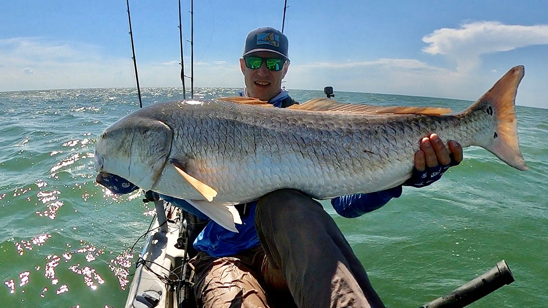 kayak angler holds up large red drum