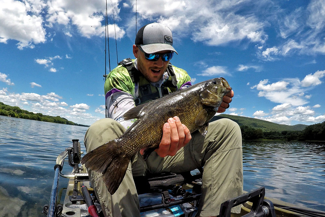 kayak angler holds up a smallmouth bass caught in its native range