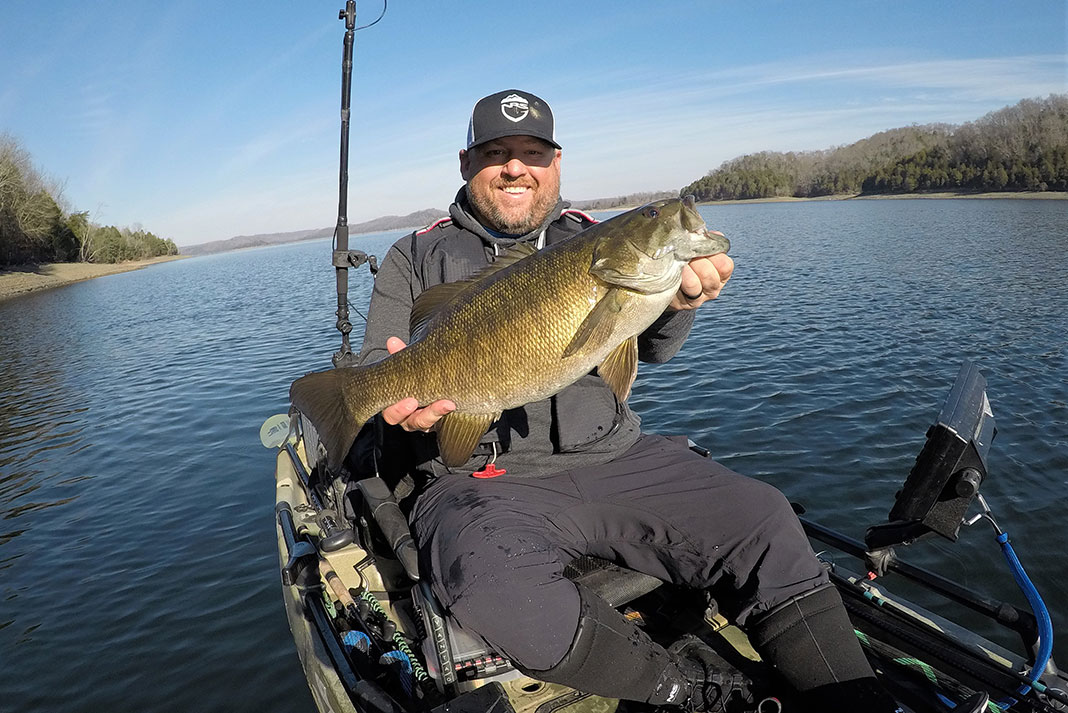 kayak angler holds up smallmouth bass caught in its native range