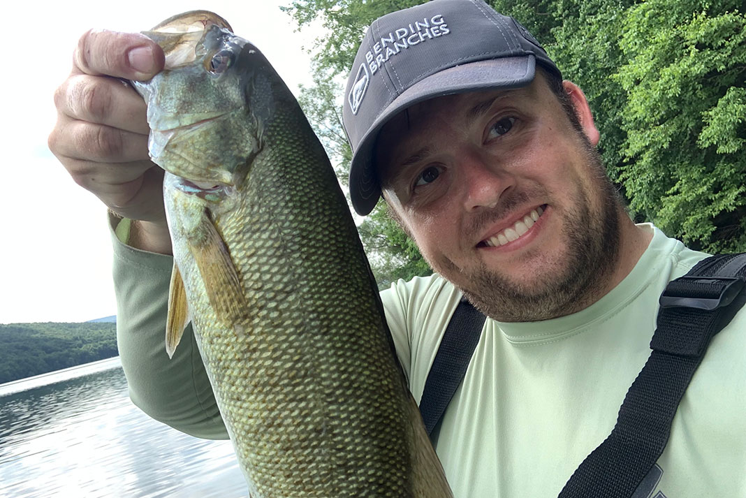 angler smiles and holds up a smallmouth bass