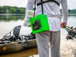 man carries Norsk batteries and fishing rods to his kayak