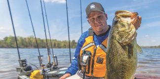 man holds up a largemouth bass caught by kayak, one of 9 varieties that make up the bass slam