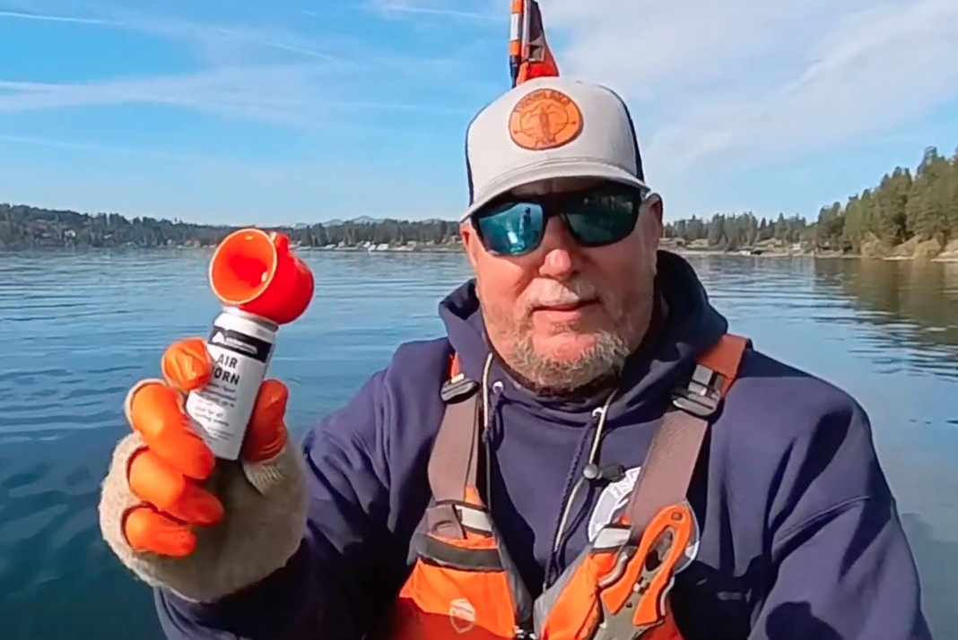 Angler holds an air horn which should be carried on a kayak.
