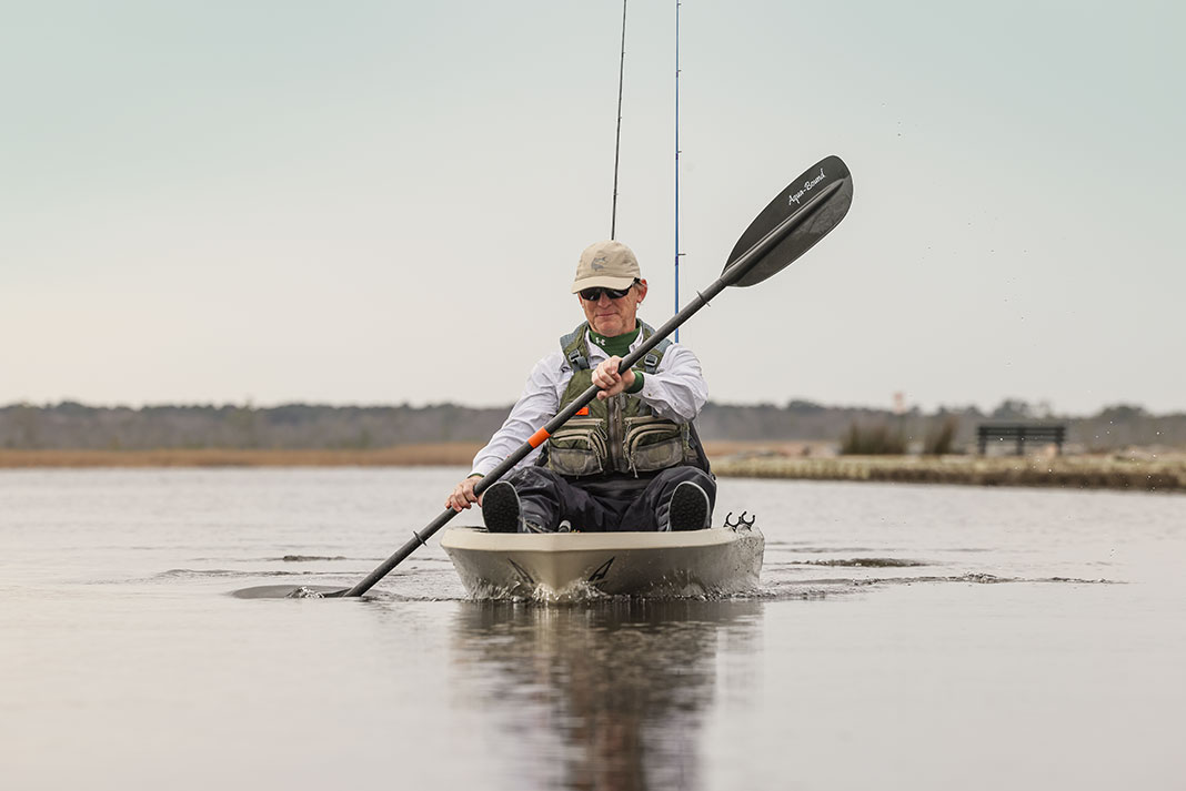 front view of a man paddling the Ascend 12T fishing kayak