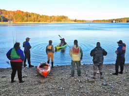 a group of anglers watch a demonstration as part of their kayak fishing courses
