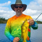 50 For 50: Chris Funk Celebrates His Half-Century With Epic Quest angler Chris Funk holds up a peacock bass while wearing a rainbow shirt