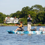 Best Tandem Fishing Kayaks For 2026 man stands and casts his fishing rod while woman sits and paddles the Feelfree Lure II tandem fishing kayak