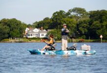 Best Tandem Fishing Kayaks For 2026 man stands and casts his fishing rod while woman sits and paddles the Feelfree Lure II tandem fishing kayak