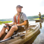 Best Fishing PFDs For 2025 two people fishing from kayaks while wearing pfds