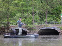 man stands and fishes from the NuCanoe Unlimited U10 compact fishing kayak near a low bridge
