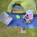 person sits with a selection of ultralight kayak camping gear