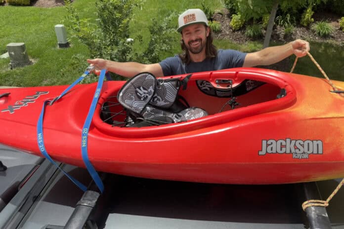 Man tying kayak to roof of car.
