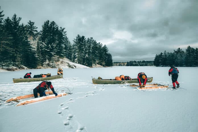 a group guided by Lure of the North takes part in canoe sledding on a frozen lake
