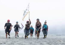 Paddle Tribal Waters youth carry a tribal flag at the mouth of the Klamath River on June 11