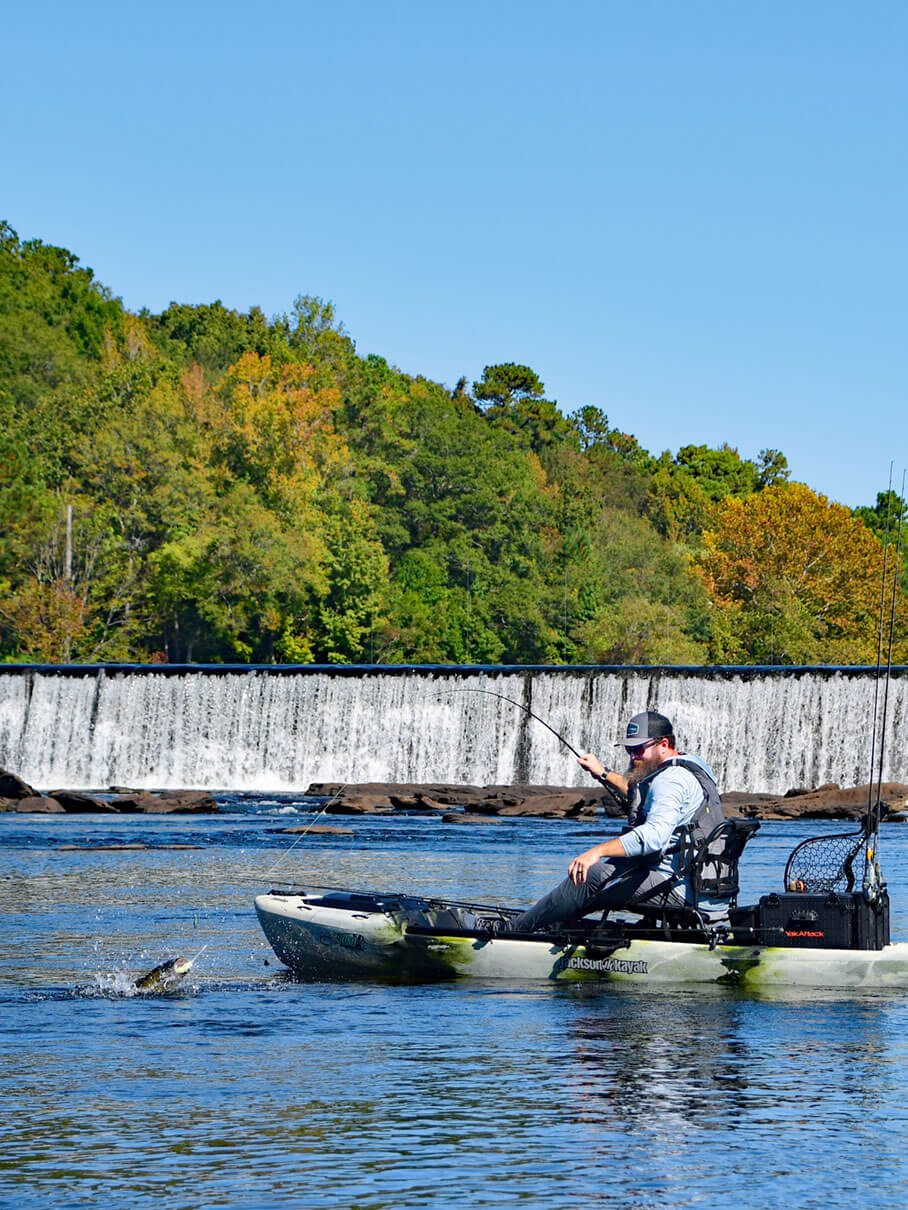 man hooks a shoal bass from a kayak while fishing downstream of a low dam