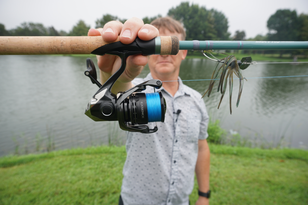 Man holding spinning rod and reel in front of him.