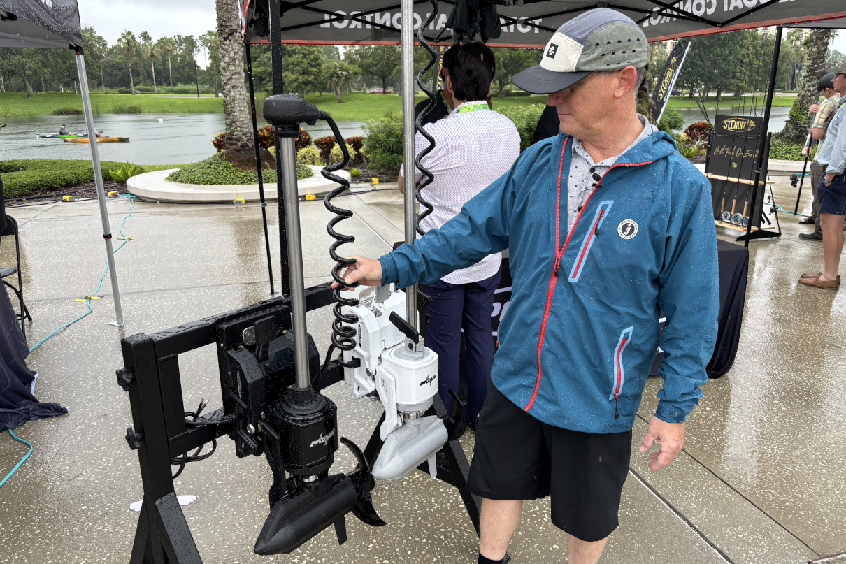 Angler in rain jacket inspects kayak motor options.