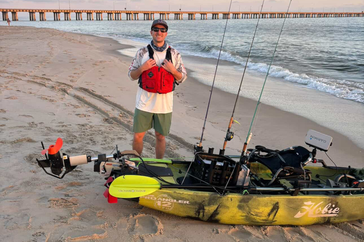 Angler preparing to launch kayak with stern-mounted motor.