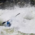 a person paddles through roaring rapids