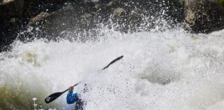 a person paddles through roaring rapids