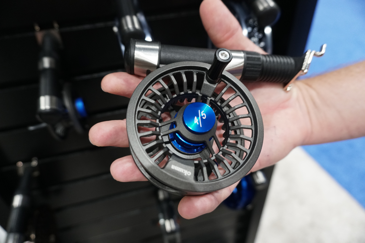 Man holding fly fishing reel in hand.