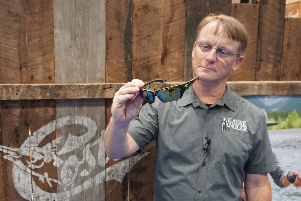 Kayak Angler editor Ric Burnley holds up a pair of Costa Del Mar Schoolie youth fishing sunglasses at ICAST 2025