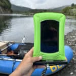 Best Waterproof Phone Pouches For 2025 Holding phone up with raft and river gorge in the background.