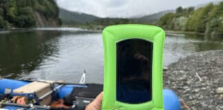 Best Waterproof Phone Pouches For 2025 Holding phone up with raft and river gorge in the background.