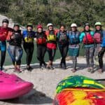 Inside India’s First All-Female Kayaking Revolution a group of woman kayakers pose for a group photo in their whitewater gear by a riverside in India