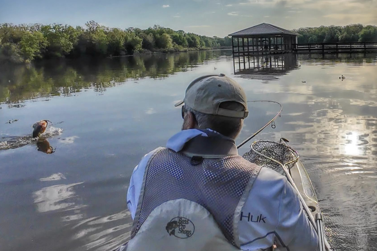 Angler catching bass during an early spring morning from a kayak.