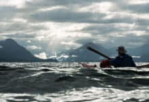 Oli Broadhead and his father cross open water in dappled light while kayaking the Inside Passage