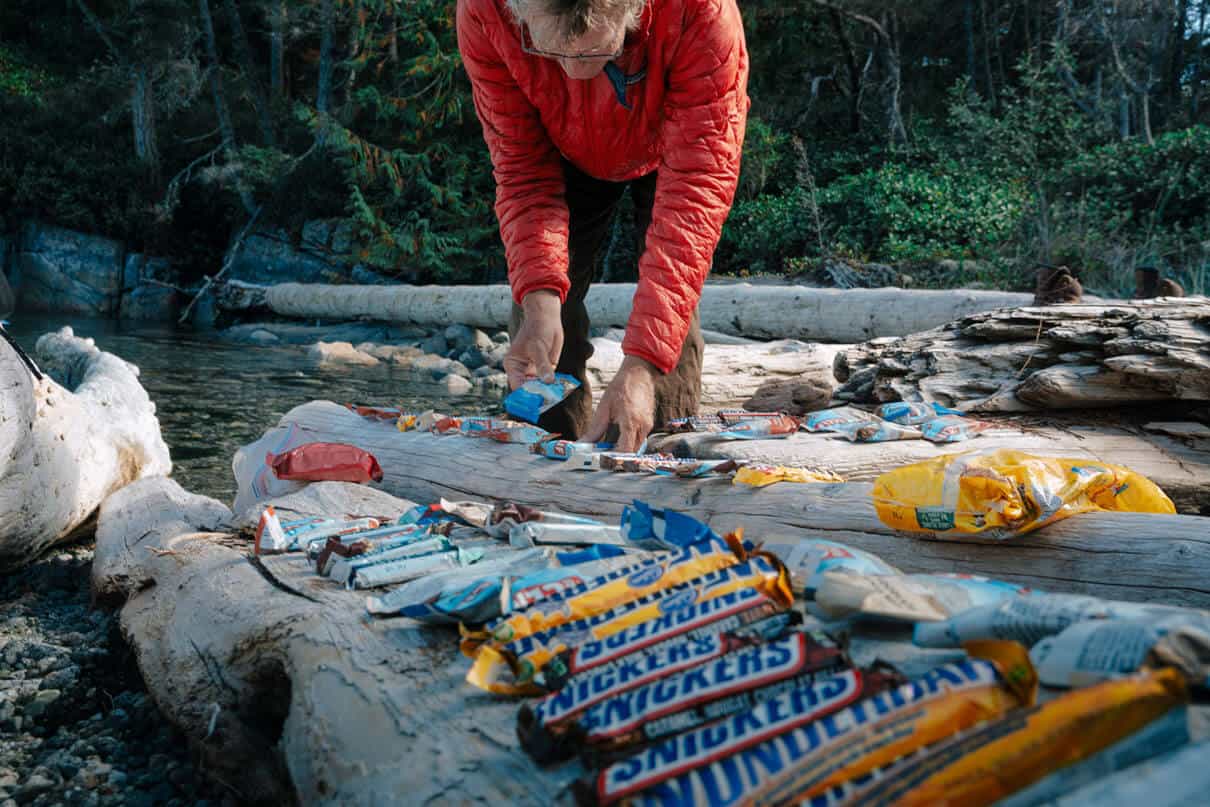 many chocolate bars are laid out on pieces of driftwood by the kayak campers