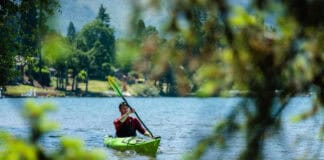 Joe Potoczak paddles the Lekker Osprey with leafy foliage in front