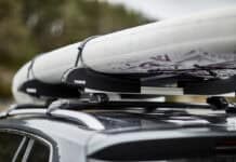 A paddleboard on top of a car's roof rack.