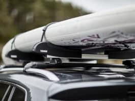 A paddleboard on top of a car's roof rack.