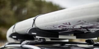 Best Paddleboard Car Racks For 2026 A paddleboard on top of a car's roof rack.