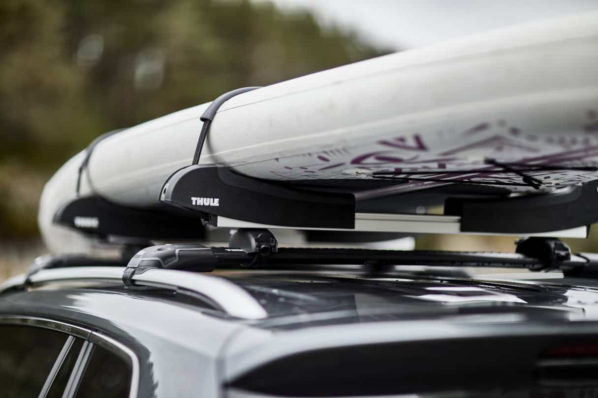 A paddleboard on top of a car's roof rack.