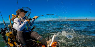 Image of Crystal Borkes on a fishing kayak pulling in a fish.