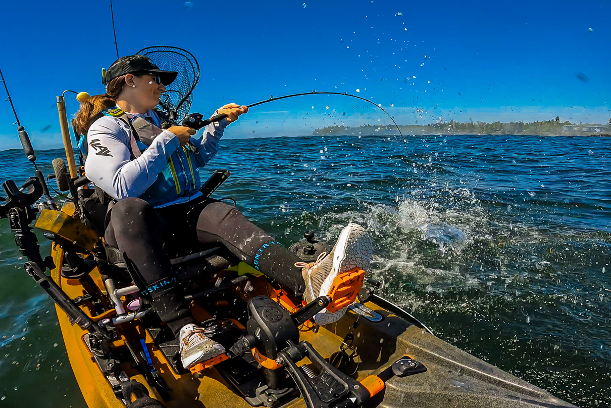 Image of Crystal Borkes on a fishing kayak pulling in a fish.