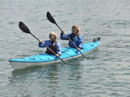 Two women paddling a tandem touring kayak.