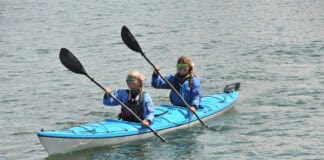 Two women paddling a tandem touring kayak.
