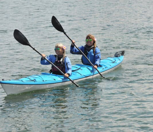 Two women paddling a tandem touring kayak.