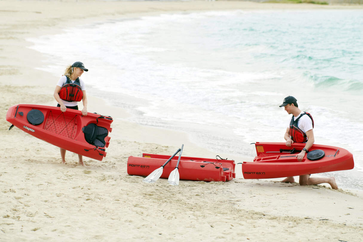 Two people assembling a kayak on a beach.
