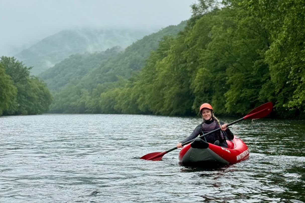 Paddler in an inflatable kayak floating down a river with NRS kayak paddle.