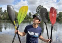 Paddling Magazine editor Joe Potoczak holding up an assortment of the best kayak paddles on the market.
