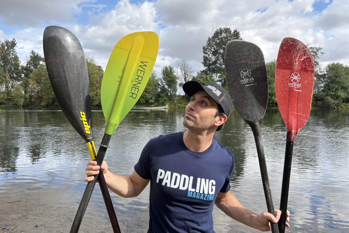 Paddling Magazine editor Joe Potoczak holding up an assortment of the best kayak paddles on the market.