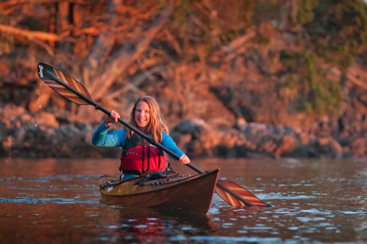 Kayaker using low angle touring paddle on a lake.