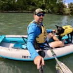 Best Inflatable Kayaks For 2026 Man and dog in inflatable kayak on river.
