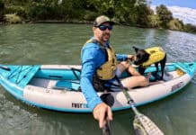 Man and dog in kayak on river.
